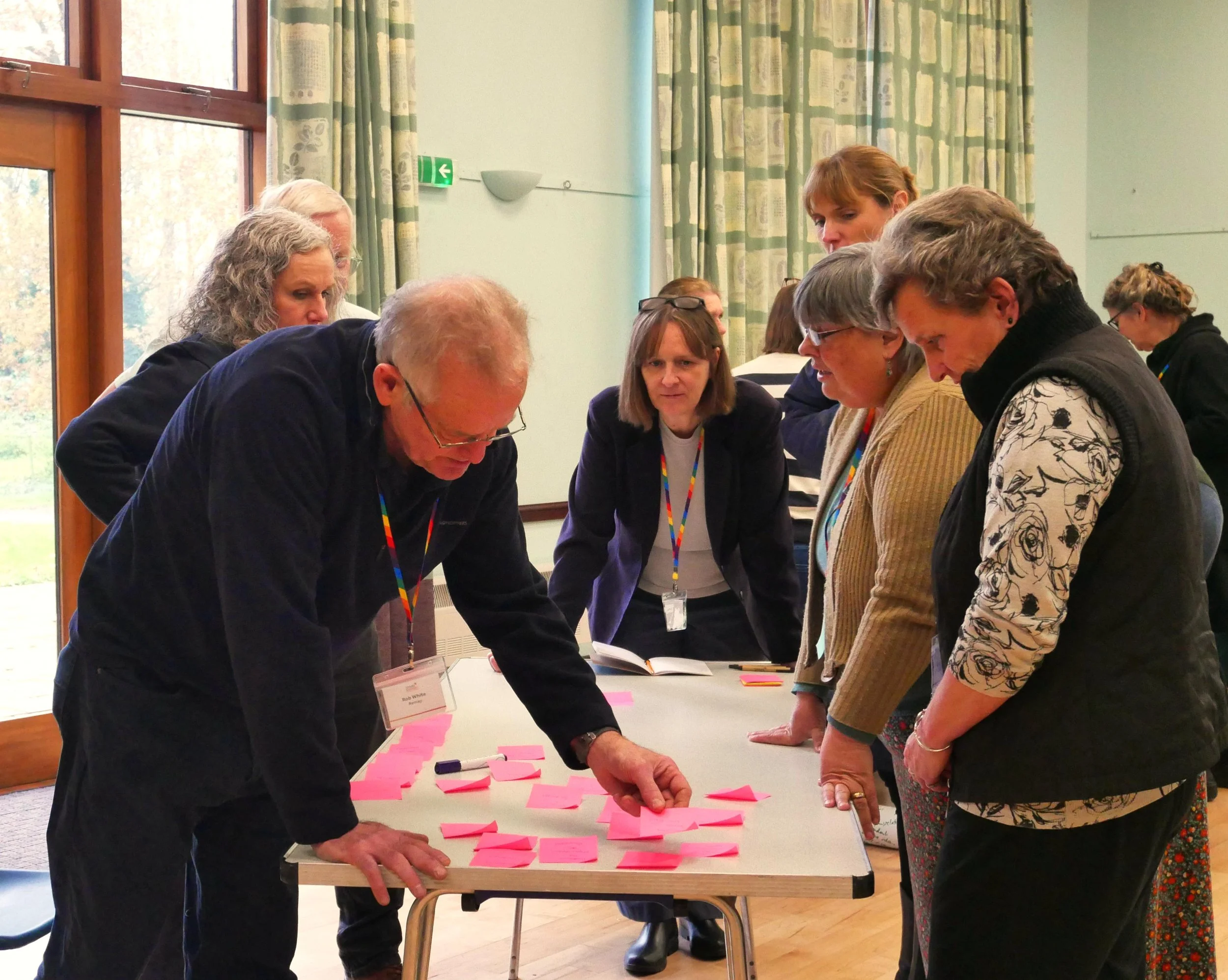 Anira Khokhar working with participants gathered around a table of notes during a workshop